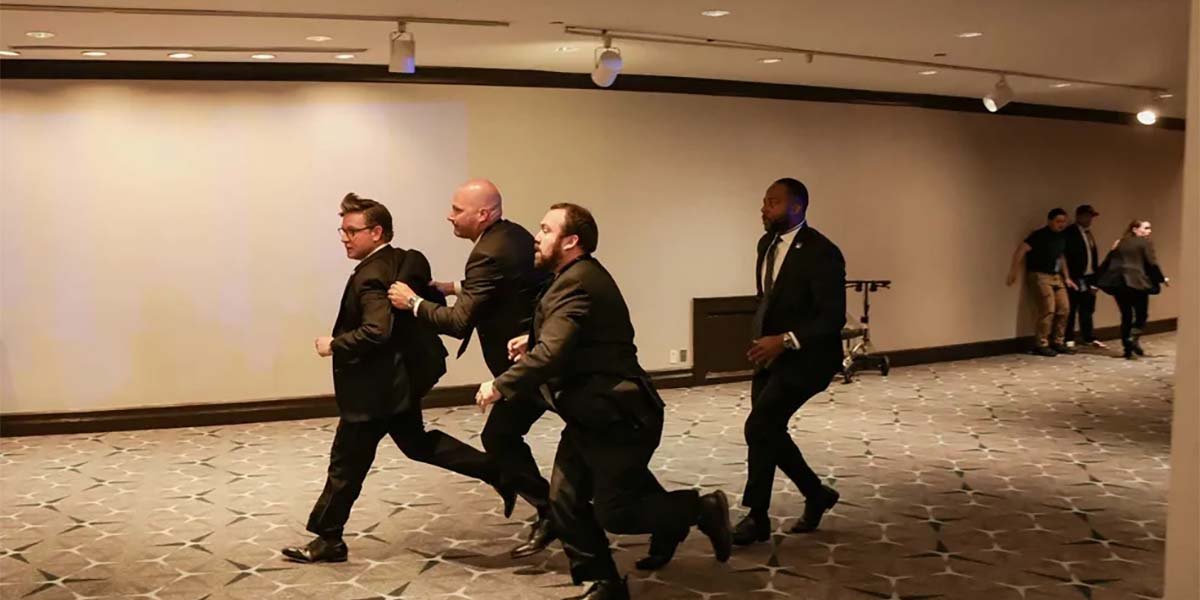 Personas agachándose bajo mesas durante una escena de pánico en una cena política formal